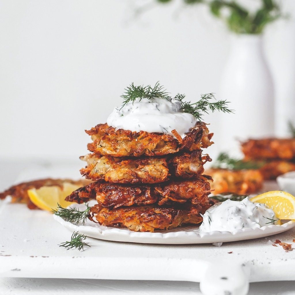 Sauerkraut latkes piled on plate with dollop of plant-based yoghurt on top