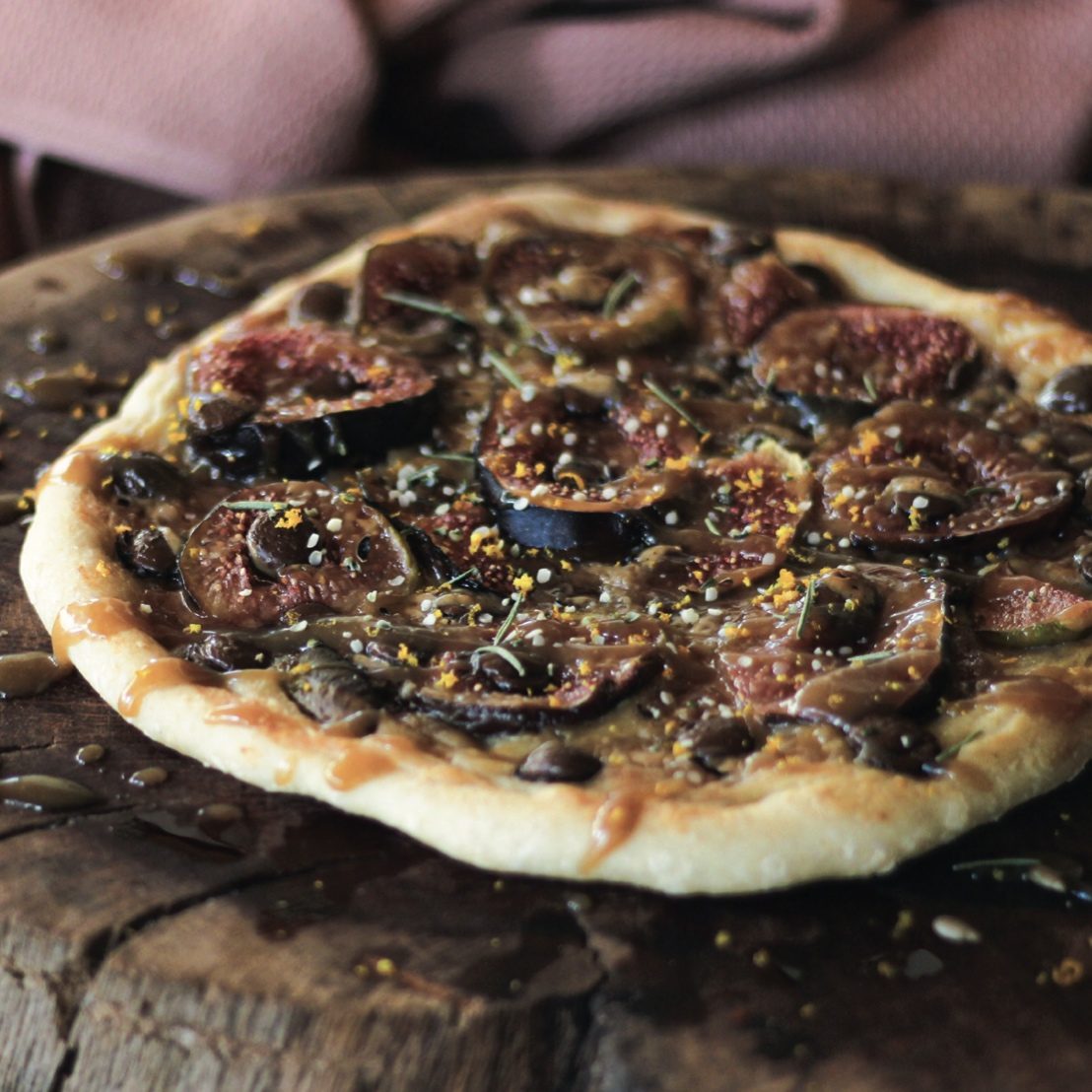 Sweet fig pizza with salted caramel and chocolate on wooden board