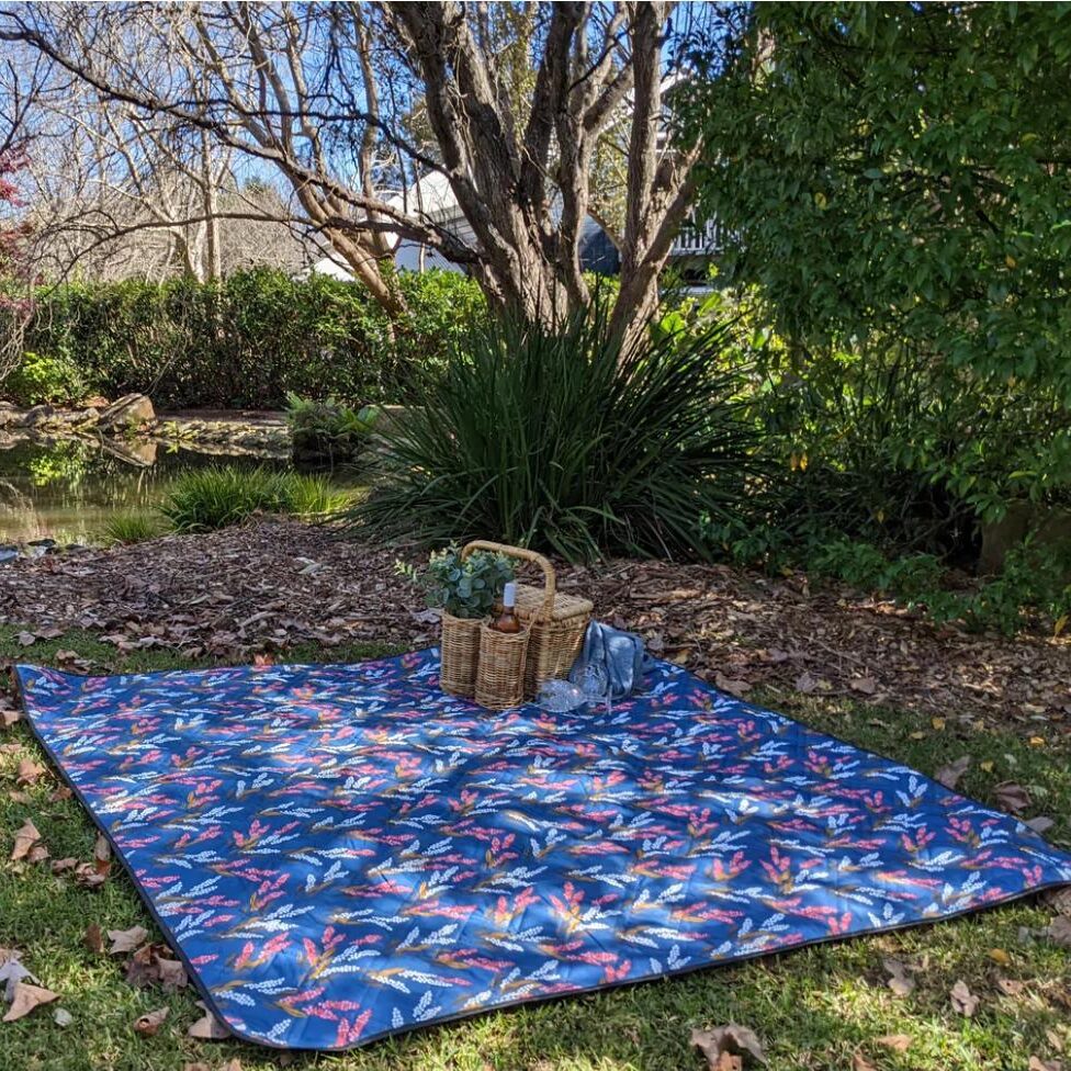 Saltwater Picnic Co. 100% recycled plastic picnic rug on grass by lake with picnic hamper