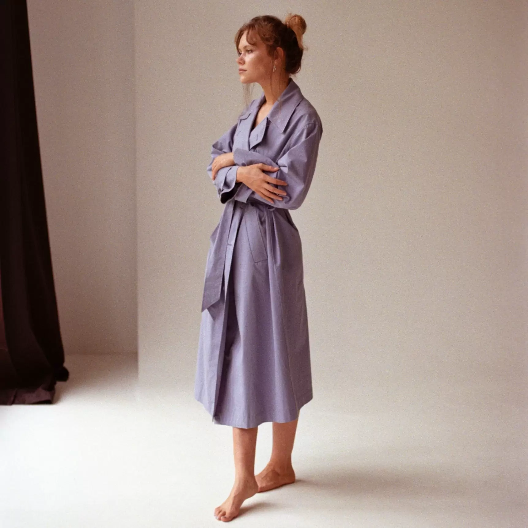 Woman in bathrobe by window