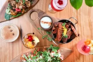 A spread from Elixiba ft several dishes and drinks on wooden table, pictured from above
