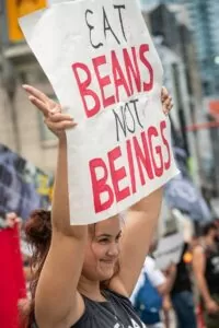 Young woman holds 'Eat beans not beings' banner at The Official Animal Rights March 