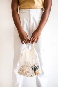 Woman holding string bag with keep cup