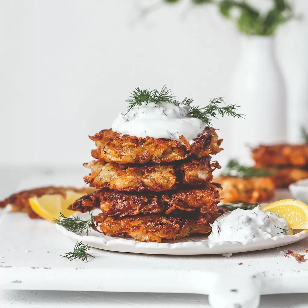 Sauerkraut latkes piled on plate with dollop of plant-based yoghurt on top