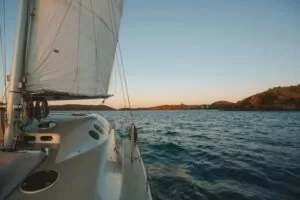Sailing boat on water, proceeding into sunset with blue-orang