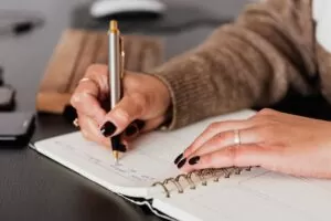 woman writing notes in notebook