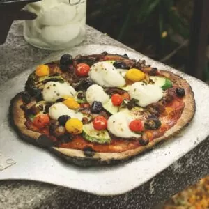 Pizza on wooden board with homemade vegan mozzarella in background